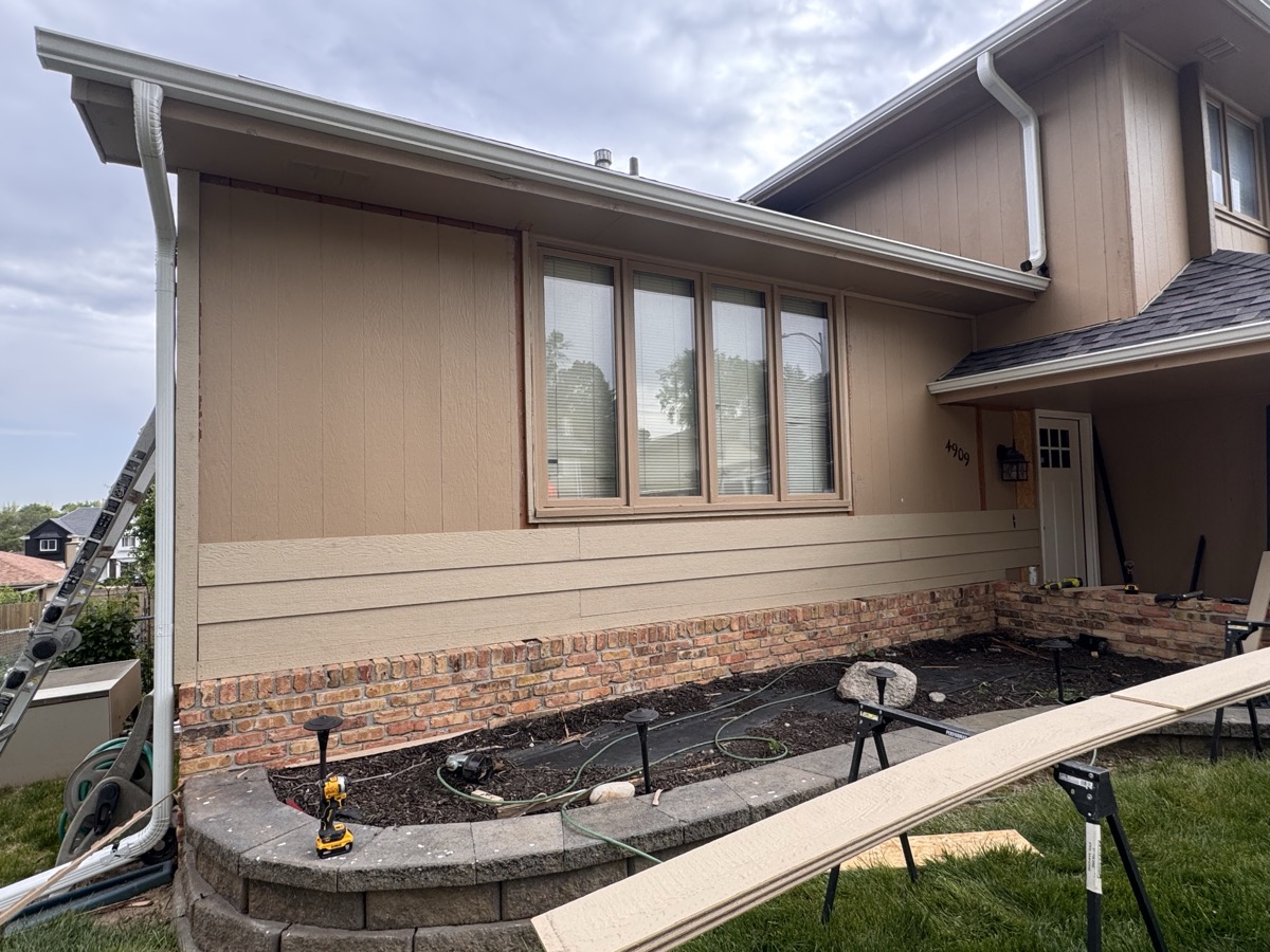 Quality siding installation transforms the look and durability of your home. A crew member aligning new siding panels on an exterior wall during a renovation project. width=
